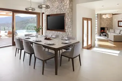 a dining room with a table and chairs and a tv at Villa Lithos in Porto Rafti