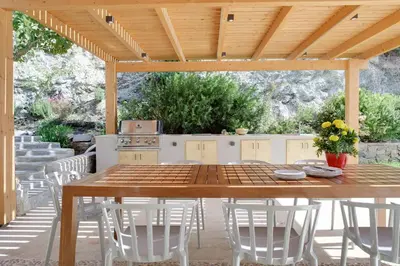 a wooden table and chairs under a wooden pergola at Villa Lithos in Porto Rafti