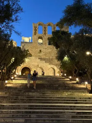 two people walking up some stairs in front of a building at Bright Koukaki Studio -10 min Walk to Acropolis in Athens