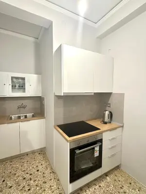 a kitchen with white cabinets and a stove top oven at Modern stay-10 mins from the city center- 5 mins from the beach in Athens