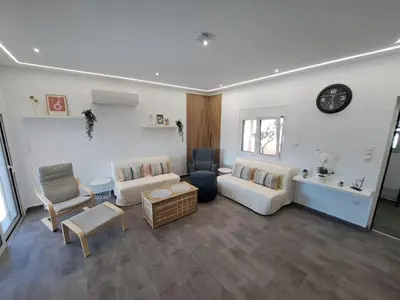 a living room with a couch and chairs and a clock at Daskalio Waves Appartment Filias in Dhaskalión