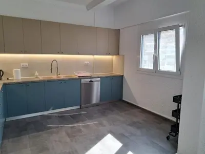 an empty kitchen with blue cabinets and a window at Daskalio Waves Appartment Filias in Dhaskalión