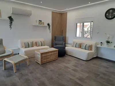 a living room with two couches and a chair and a clock at Daskalio Waves Appartment Filias in Dhaskalión