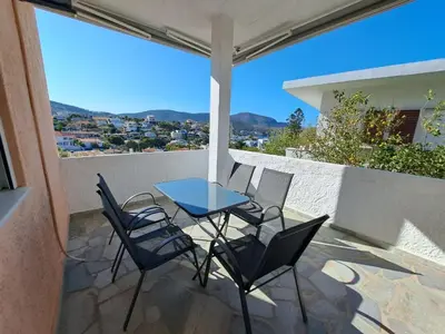 a patio with a table and chairs on a balcony at Daskalio Waves Appartment Filias in Dhaskalión