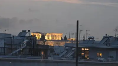 a city with a building in the background with smoke at Acropolis View Studio Varnava in Athens
