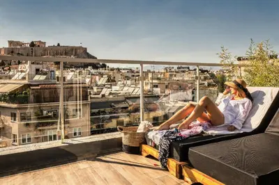 a woman sitting on a bench on a balcony talking on a cell phone at Penthouse Studio Acropolis View in Athens