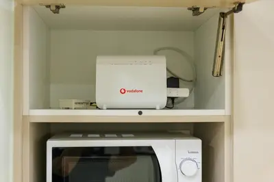 a kitchen with a microwave and a laptop on a shelf at 2 BR Apartment with Sitcom Vibes VIPGreece in Athens