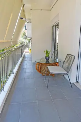a balcony with a glass table and a chair at The North - Floor apartment in Kato Halandri in Athens
