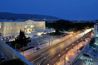 a city street at night with street lights and buildings at White Rose Athens Residence in Athens