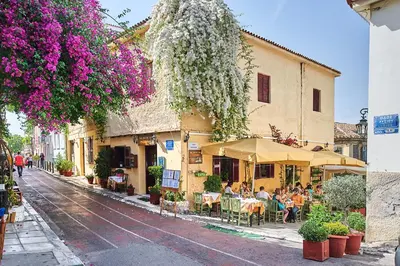 a street with people sitting at tables outside a building at White Rose Athens Residence in Athens