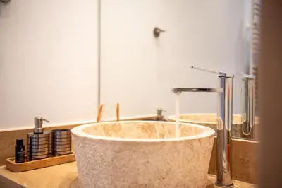 a bathroom with a stone sink with a faucet at AeroHill Suites Near Athens Airport By SEM in Artemida