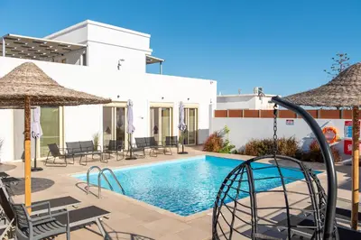 a pool with chairs and umbrellas next to a building at AeroHill Suites Near Athens Airport By SEM in Artemida