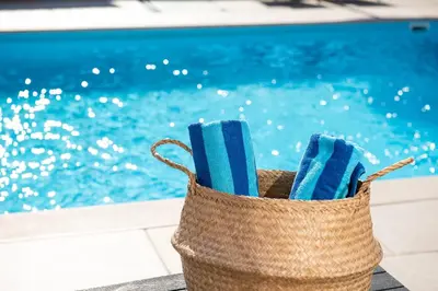 a basket filled with blue towels next to a swimming pool at AeroHill Suites Near Athens Airport By SEM in Artemida