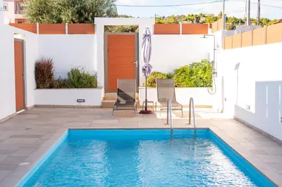 a swimming pool in the middle of a patio with a house at AeroHill Suites Near Athens Airport By SEM in Artemida