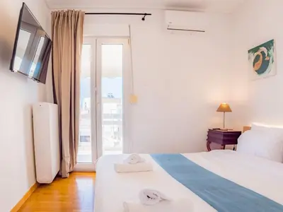 a white bedroom with a bed and a window at Kolonaki Penthouse - Acropolis View - 5min Metro in Athens
