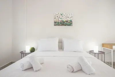 a white bedroom with a white bed with two pillows at 2 bedroom apt at Patisia metro station! in Athens