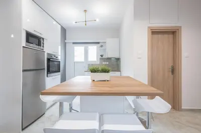 a kitchen with a wooden table and white chairs at 2 bedroom apt at Patisia metro station! in Athens