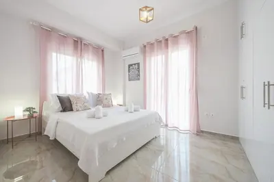 a white bedroom with a large bed with two candles on it at 2 bedroom apt at Patisia metro station! in Athens