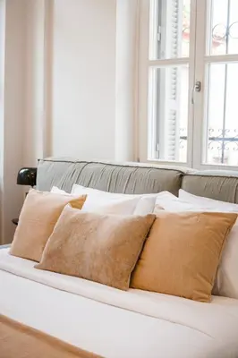 a white bed with brown pillows on it at Historic Villa with Hot Tub Beneath the Acropolis in Athens