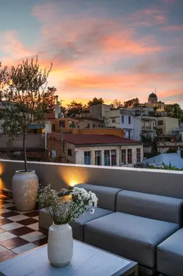 a sunset on a rooftop with a couch and flowers at Historic Villa with Hot Tub Beneath the Acropolis in Athens