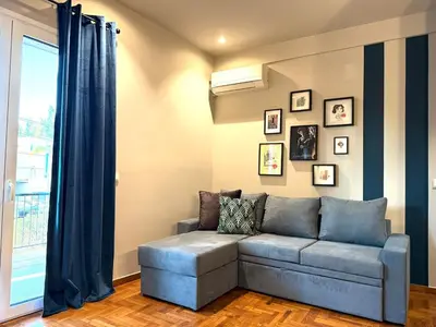 a living room with a blue couch and a window at Cosy, Athens core fully renovated apartment in Athens