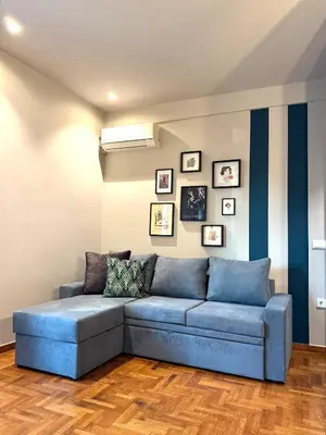 a blue couch in a living room with pictures on the wall at Cosy, Athens core fully renovated apartment in Athens