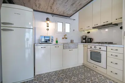 a kitchen with white cabinets and a refrigerator at City Panorama Studio by ΜΡS in Athens