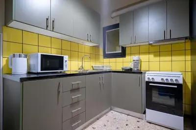 a kitchen with white cabinets and yellow tiles at Warm 2BR Apt - Central Kypseli by ΜΡS in Athens