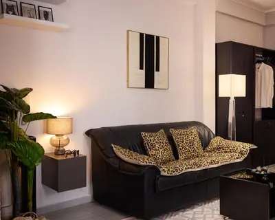 a black couch with leopard pillows in a living room at Sofokleous central studio in Athens