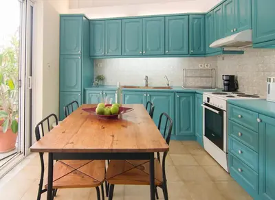 a blue kitchen with a wooden table with a bowl of fruit at City Garden Escape with a View! in Athens