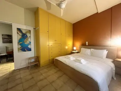 a bedroom with a large bed with a yellow wall at City Garden Escape with a View! in Athens