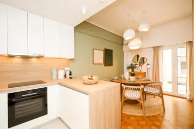 a kitchen with white cabinets and a table with chairs at Kallimarmaro Gem II in Athens