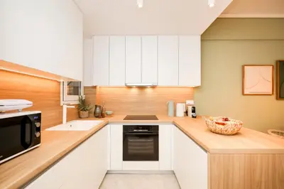 a kitchen with white cabinets and a sink and a microwave at Kallimarmaro Gem II in Athens