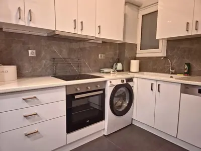 a kitchen with white cabinets and a washing machine at City Harmony Flat in Athens