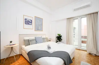 a white bedroom with a large bed and a window at Kallimarmaro Gem III in Athens