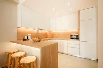 a kitchen with white cabinets and a counter with stools at Kallimarmaro Gem I in Athens