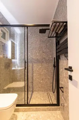 a glass shower door in a bathroom with a toilet at Kallimarmaro Gem I in Athens