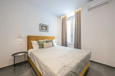 a bedroom with a large bed and a stool at Piraeus Apartment in Piraeus