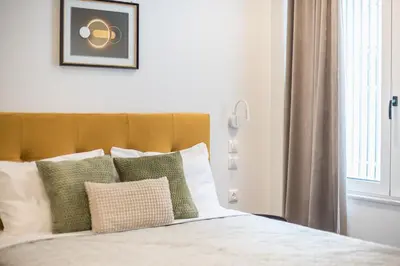 a bed with green and white pillows and a window at Piraeus Apartment in Piraeus