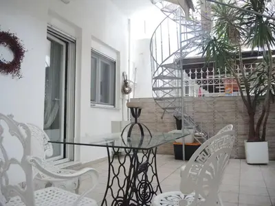 a glass table and white chairs on a patio at Long-Stay Family & Work Oasis -20 min to Center & Sea in Piraeus
