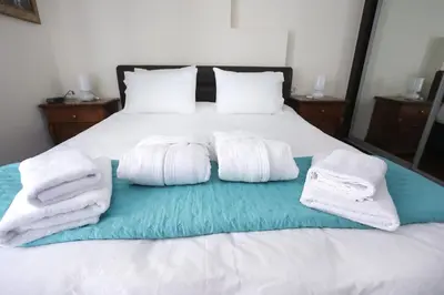 a bed with white towels on top of it at Cosy and Comfy near Niarxos and Athens Riviera in Athens