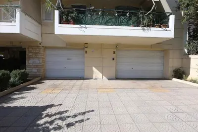 a building with two garage doors and a balcony at Cosy and Comfy near Niarxos and Athens Riviera in Athens