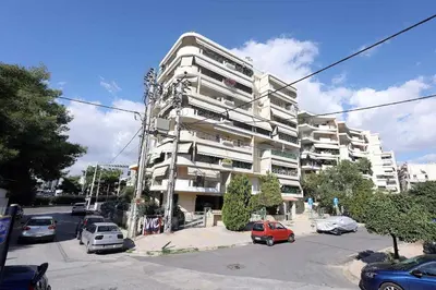a large apartment building with cars parked in a parking lot at Cosy and Comfy near Niarxos and Athens Riviera in Athens