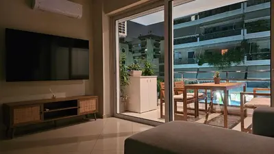 a living room with a television and a table with chairs at Triton apartment in Athens