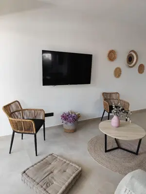 a living room with two chairs and a tv on a wall at Αriadne in Porto Rafti