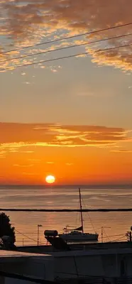 a boat sitting on the water at sunset at Aghia Marina, Aegina Studio in Aegina Town
