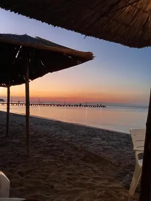 a beach with an umbrella and chairs and the ocean at Aghia Marina, Aegina Studio in Aegina Town