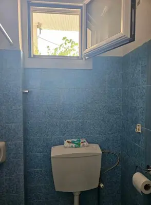 a blue bathroom with a toilet and a window at Aghia Marina, Aegina Studio in Aegina Town