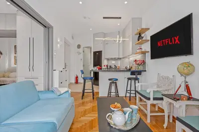 a living room with a blue couch and a kitchen at h2h Kalypso #Luxury smART, hi-tec, with parking, in 1'metro in Piraeus