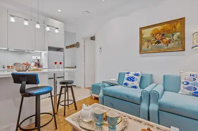 a living room with a blue couch and a kitchen at h2h Erato #Luxury, tech, smART with parking, in 1' metro in Piraeus